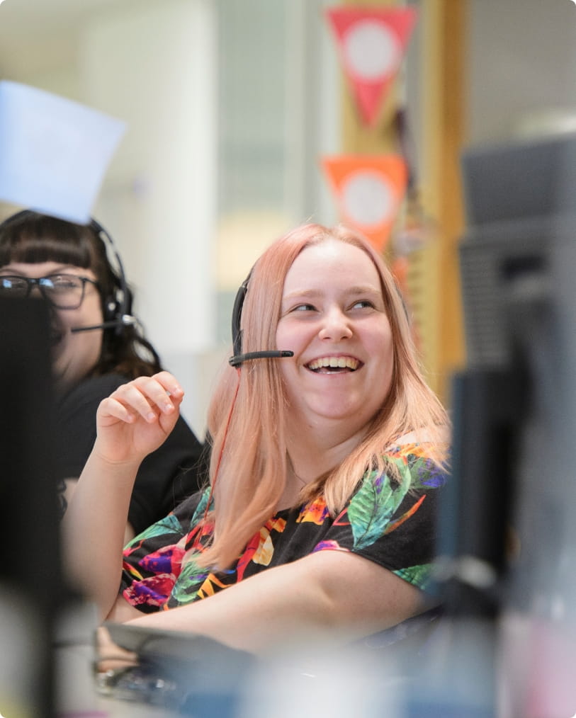 Here to help!  This photograph shows someone in the Homelet call centre, smiling at someone off camera whilst wearing a headset.