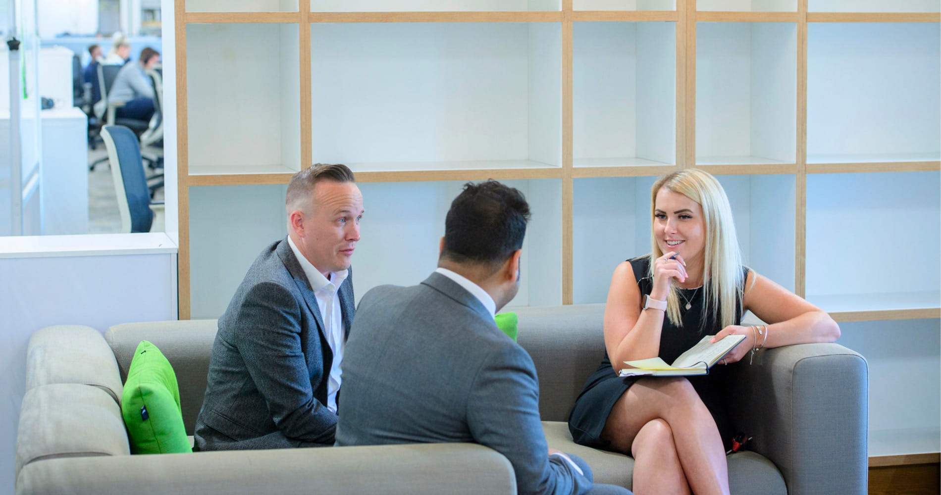 3 team members sitting on sofas in mid conversation and smiling