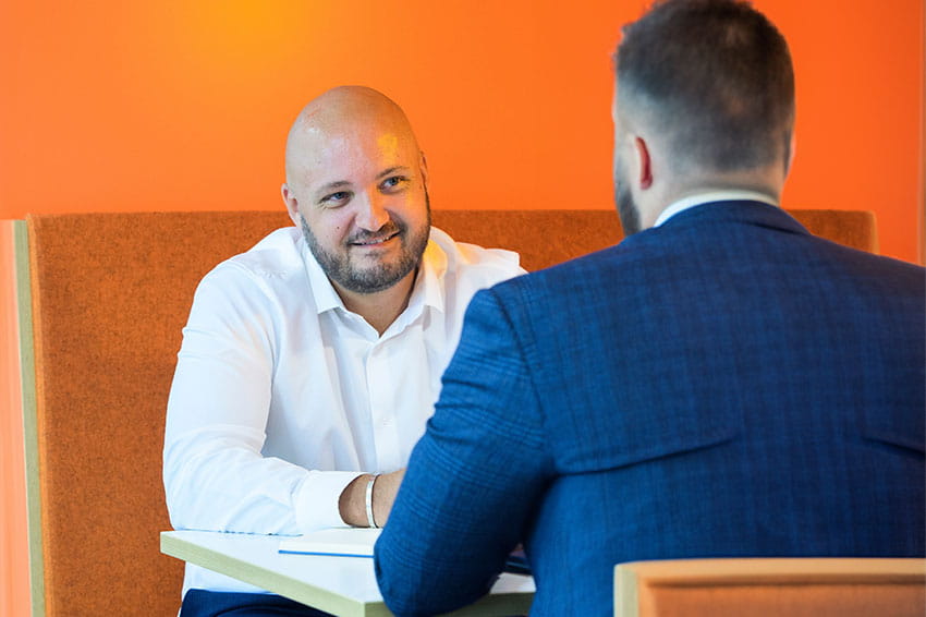 HomeLet colleague having a formal chat in an orange booth