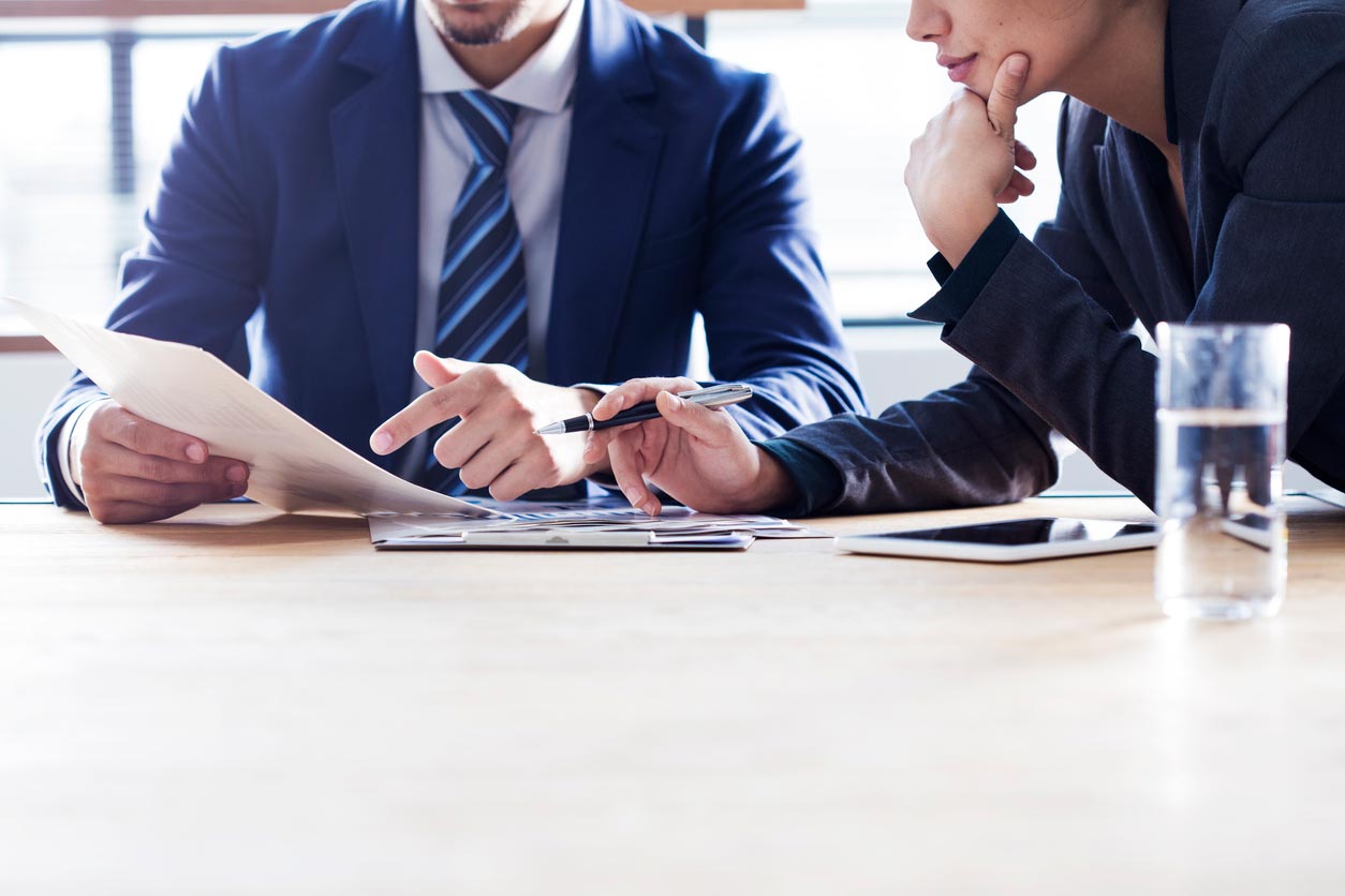 This photo shows two people looking at a piece of paper that one of them is holding.