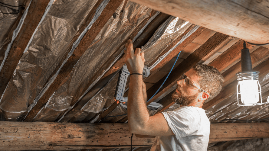 A photograph of a person putting insulation into a ceiling.