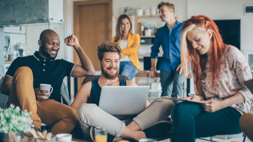 This photo shows 3 people sitting on a sofa in the foreground and two people in the background.