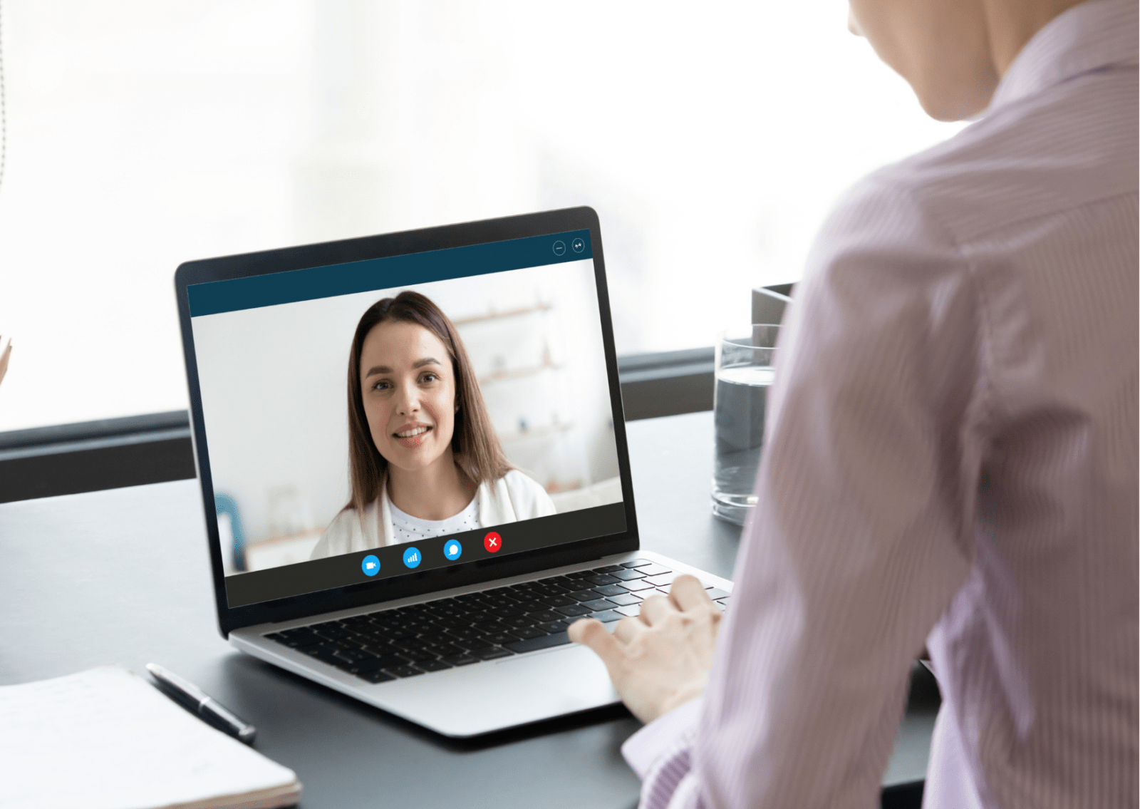 A photograph of someone conducting a virtual meeting on a laptop, which shows a second person on its screen.