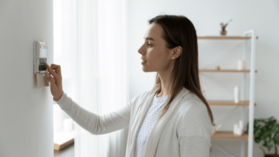 A woman setting the temperature at her home