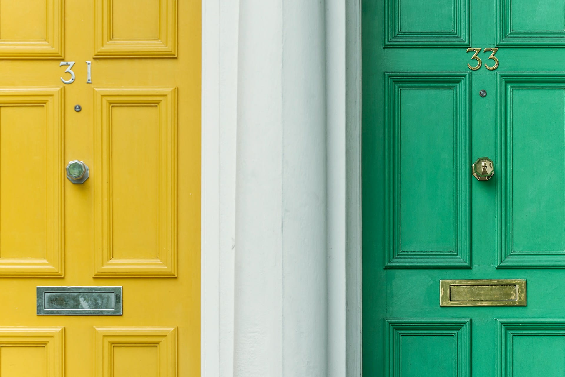 Two front doors next to each other, symbolising the choice between a rent guarantor and rent guarantee insurance.