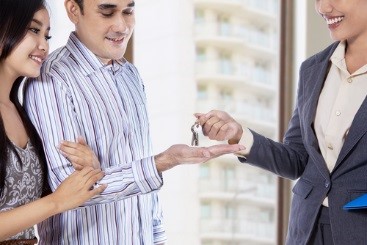 Smiling landlord handing keys to tenants